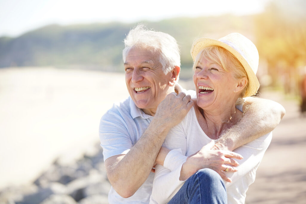 Elderly couple smiling together on the beach