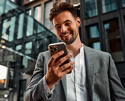 Man in suit smiling while using smartphone