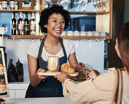 Two women smiling and talking over coffee