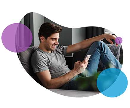 Man smiling while using smartphone on couch with abstract background