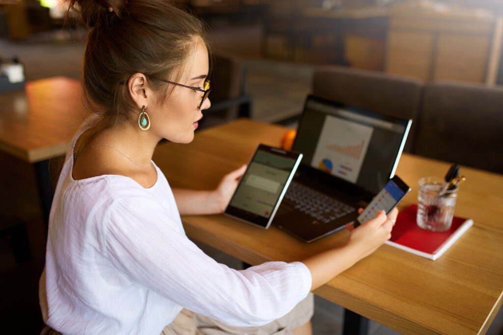 Woman working at desk with smart devices and taking notes