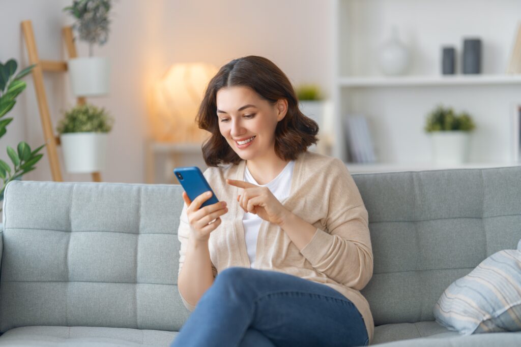 Woman sitting on couch smiling at phone